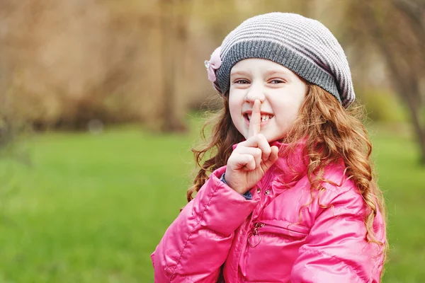 Little girl putting finger up to lips.