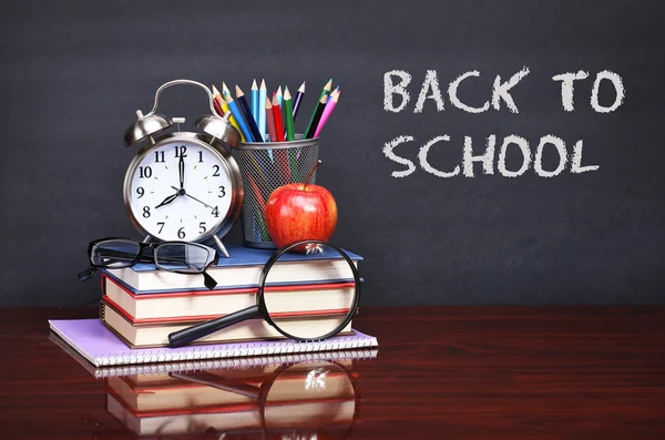 Books, apple, alarm clock and pencils on wood desk table. Text b