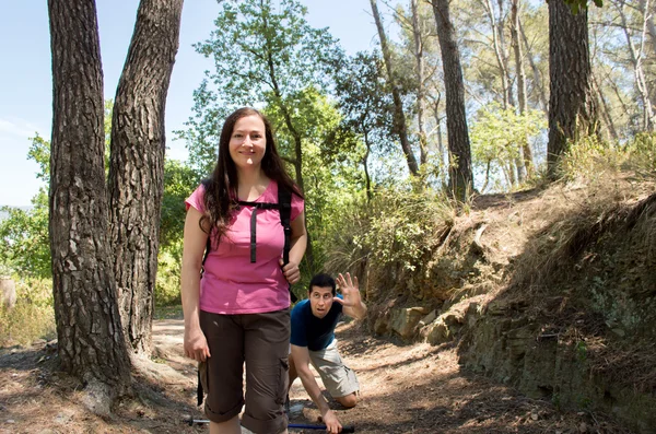 Hiker woman smiling on the forest and man has an accident