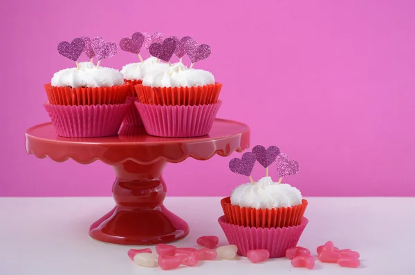 Pink and white cupcakes with heart shape toppers.