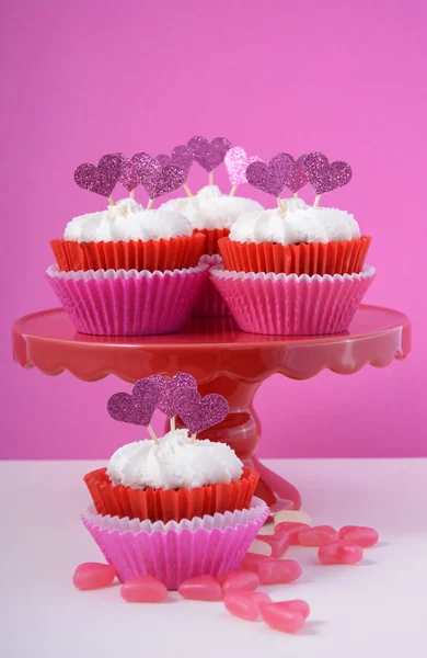 Pink and white cupcakes with heart shape toppers.