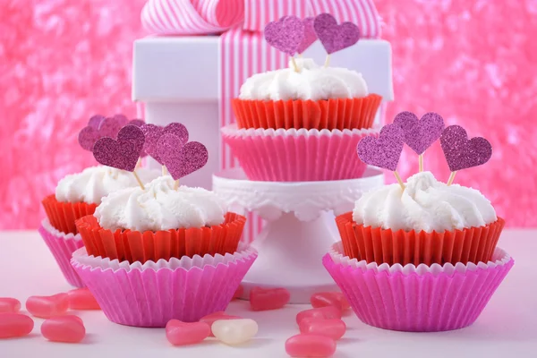 Pink and white cupcakes with heart shape toppers.