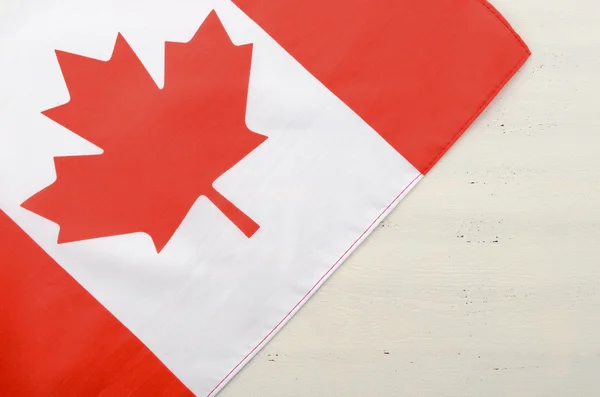 Canadian red maple leaf flag on white wood background.
