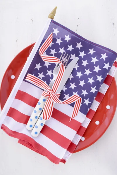 USA party table place setting with flag on white wood table.