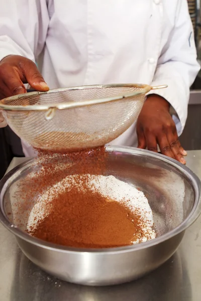 Close up of sifting cocoa into flour mix