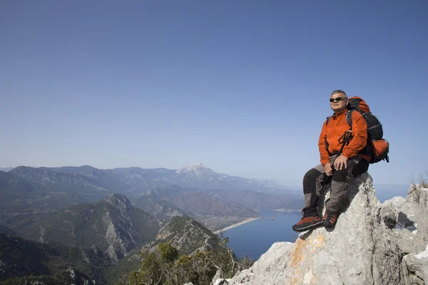 A traveler stands on top of a mountain and looks out to sea.