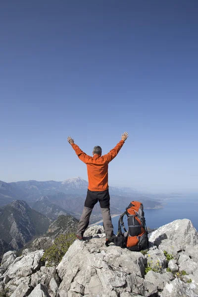 A traveler stands on top of a mountain and looks out to sea.