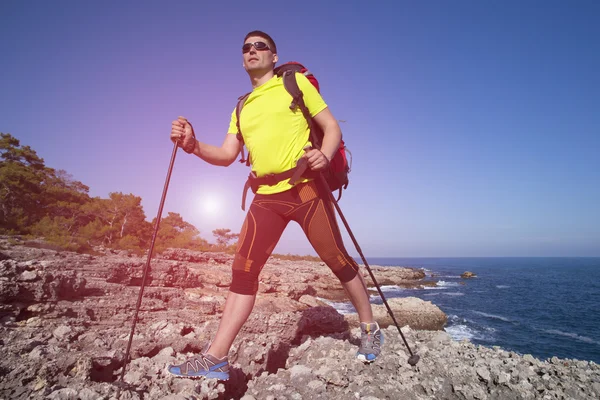 A traveler stands on top of a mountain and looks out to sea.