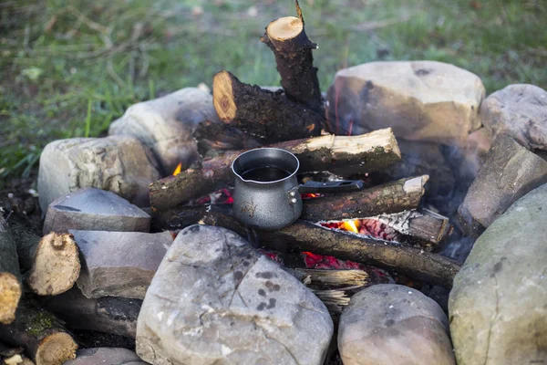 Camping.Girl sitting near a campfire at the campsite looking at map and drinking coffee.