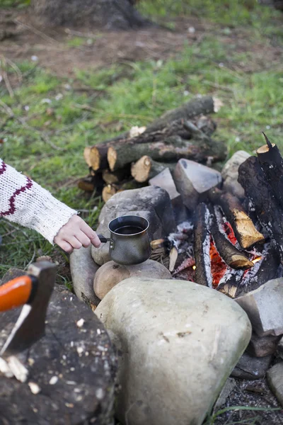 Girl sitting near a campfire at the campsite looking at map and drinking coffee.