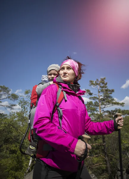 Mom walks in the forest with a child, a child in the children carry.