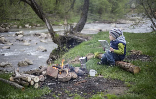 Teenager sitting near a fire in camping and watching map.