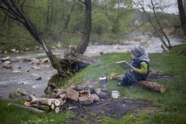 Teenager sitting near a fire in camping and watching map.