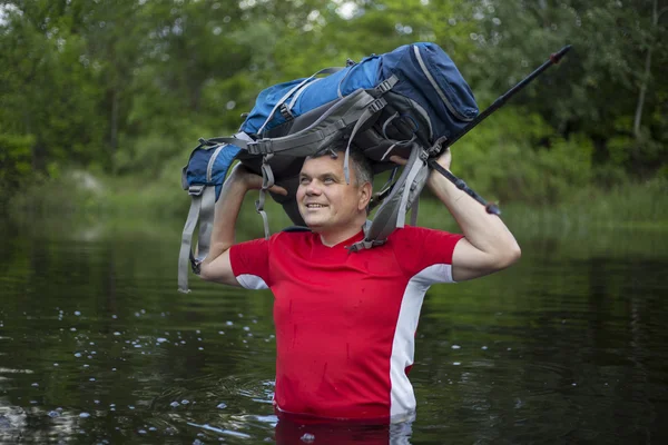 Hiker man crossing the river to reach the other side