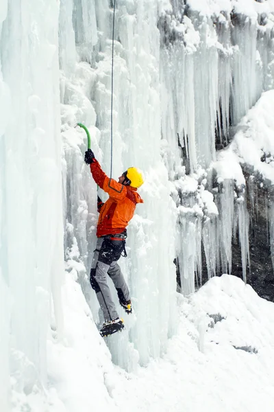 Ice climbing.Man climbing frozen waterfall.