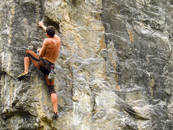 Cliffhanger.Young male climber hanging by a cliff.