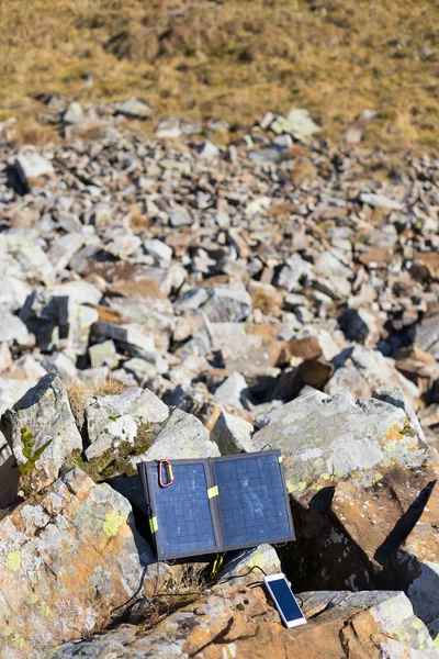 Solar panel.The solar panel attached to the tent. The man sitting next to mobile phone charges from the sun.