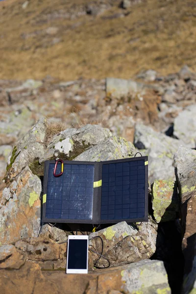 Solar panel.The solar panel attached to the tent. The man sitting next to mobile phone charges from the sun.