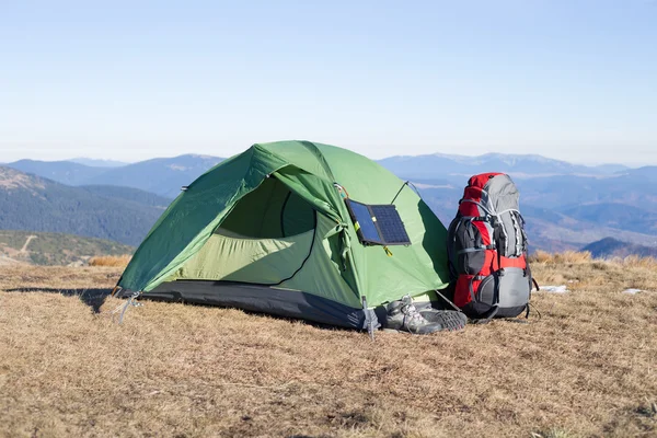 The solar panel attached to the tent. The man sitting next to mobile phone charges from the sun.