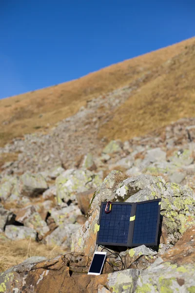 The solar panel attached to the tent. The man sitting next to mobile phone charges from the sun.