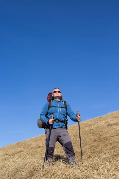 Man hiking in the mountains with a backpack and tent.