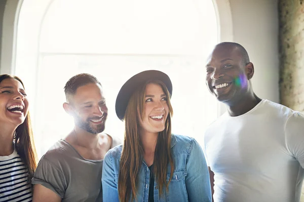 Laughing friends standing together by window