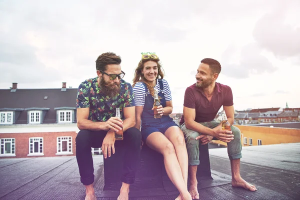 Two men and a woman drinking beer together on roof