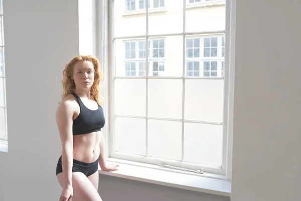 Woman in fitness attire standing by a window