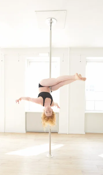 Woman doing pole dance in a pole fitness class