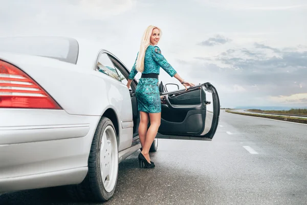 Blonde woman stay near car