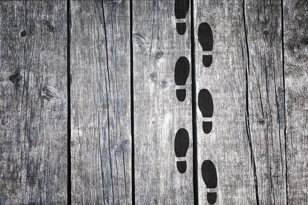 Black shoeprints on old wooden floor