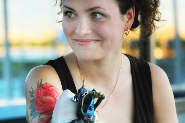 Tattooer showing process of making a tattoo on young beautiful  woman