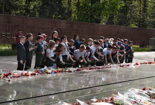 Schoolchildren put flowers to the eternal fire at the memorial