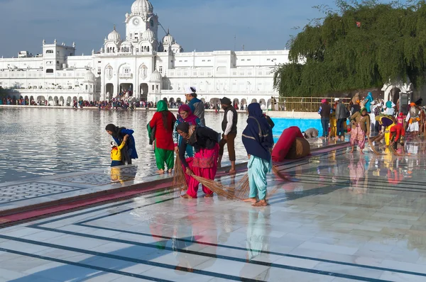Indian women clean floor near Golden Temple before the evening prayer. Amritsar