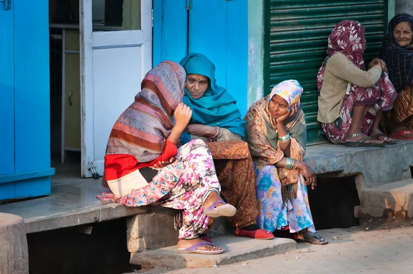 Indian women sit and chat on a house porch