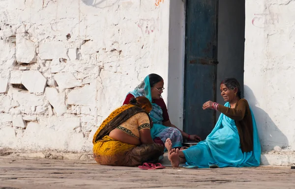 Indian women sit and chat on a house porch