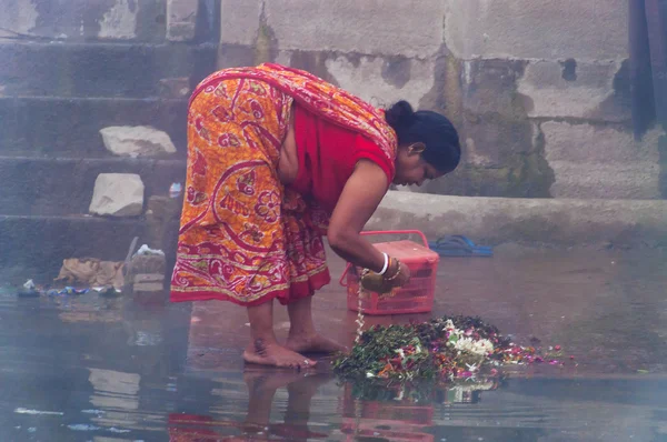Indian woman taking ritual bath in the river Ganges at cold foggy winter morning. Varanasi