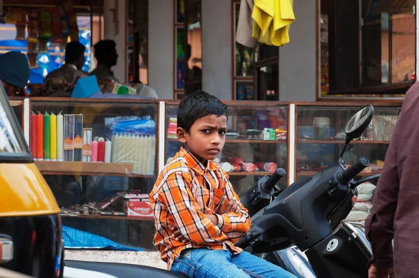 Indian young boy sitting on the bike at the Russell market in Bangalore