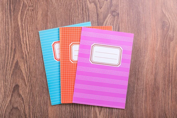 Colored exercise books on the blue wooden background