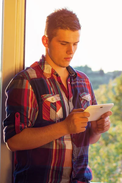 Man standing near window at sunshine using tablet