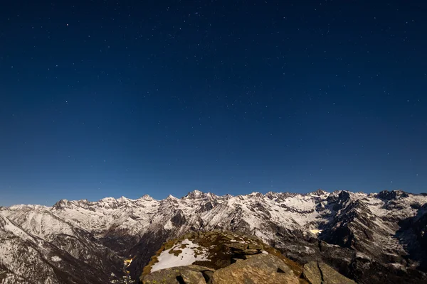 The starry sky above the Alps in winter under moonlight