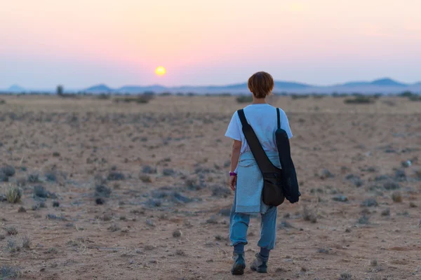 Tourist walking in the Namib desert at sunset, Namib Naukluft National Park, Namibia. Adventure and exploration in Africa.