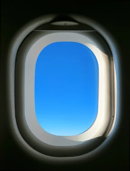 Plane window with blue sky in it