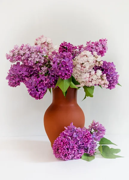 Beautiful bouquet of lilac in a clay vase.