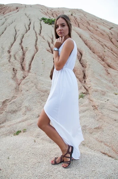 A beautiful girl in a white dress by the hill