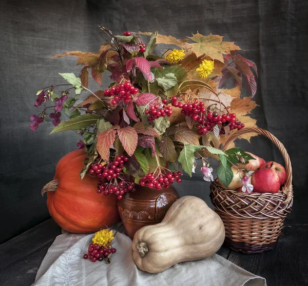 The autumn bouquet of leaves, flowers and fruits on a wooden table