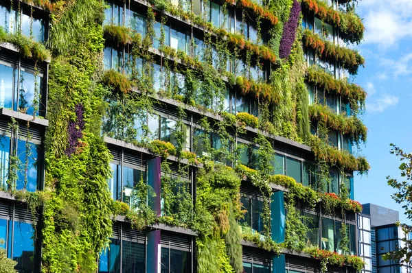 Green skyscraper building with plants on the facade