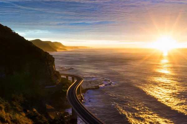 Sea cliff bridge along Australian Pacific ocean coast on sunrise