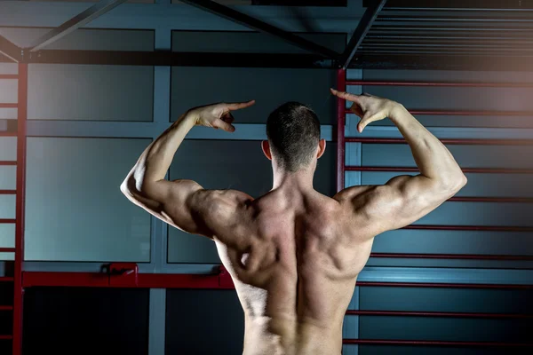 Man posing in gym showing back