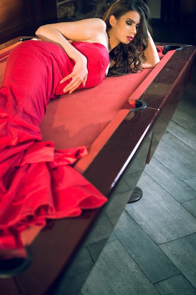 Red dress girl lying on billiard table